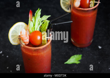 Bloody Mary Cocktail in bicchieri con contorni. Il pomodoro Bloody Mary bevanda piccante su sfondo nero con copia spazio. Foto Stock