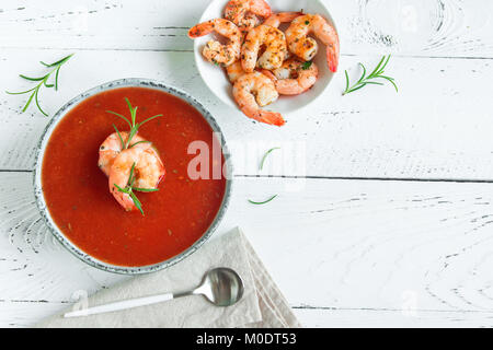 Vegetali zuppa di pomodoro gazpacho con gamberi (gamberetti) e rosmarino in ciotola di legno bianco sfondo, vista dall'alto, copia dello spazio. Foto Stock