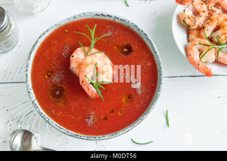 Vegetali zuppa di pomodoro gazpacho con gamberi (gamberetti) e rosmarino in ciotola di legno bianco sfondo, vista dall'alto, copia dello spazio. Foto Stock