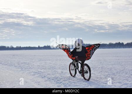 Una persona in sella a una moto con ali di farfalla all'arte Shanty progetti sul lago ghiacciato di Harriet a Minneapolis, MN, Stati Uniti d'America. Foto Stock