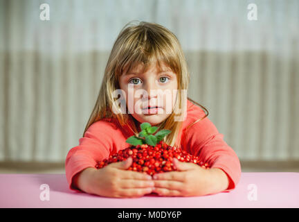 Una bambina con fragole selvatiche, sullo sfondo luminoso Foto Stock