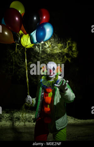 Foto di sorridere clown con palloncini colorati di notte Foto Stock