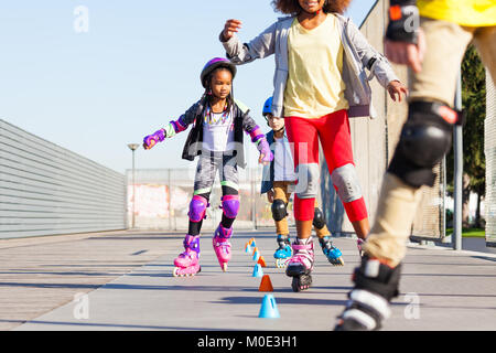 I bambini ad imparare a slalom skate con pattini a rotelle in linea Foto Stock