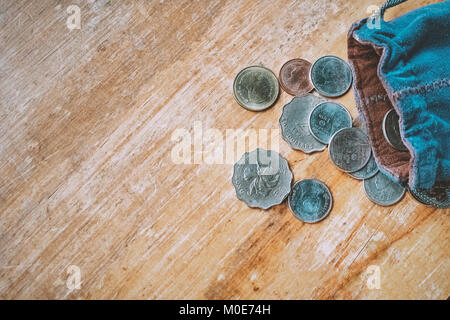 Thai e Hong Kong monete in tessuto blu borsa sul tavolo di legno. Foto Stock