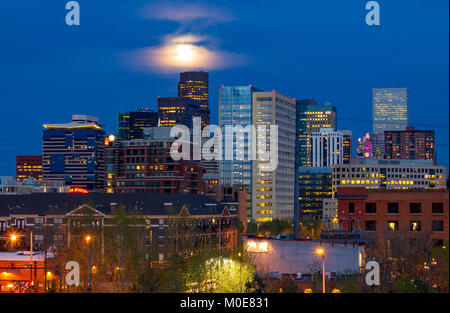 Luci colorate di Denver in Colorado skyline del centro di notte con la luna piena incandescente nel cielo serale in background Foto Stock