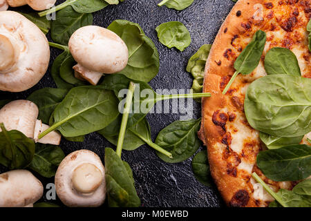 Close up vista dall'alto della pizza coperto con foglie di spinaci accanto a m Foto Stock