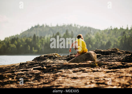 Ragazza giovane giocando sulle rocce da un lago Foto Stock