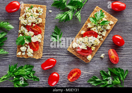 Fette biscottate con formaggio blu e pomodori Foto Stock