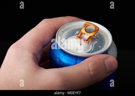 Macro di aprire la birra può con schiuma in man mano Foto Stock