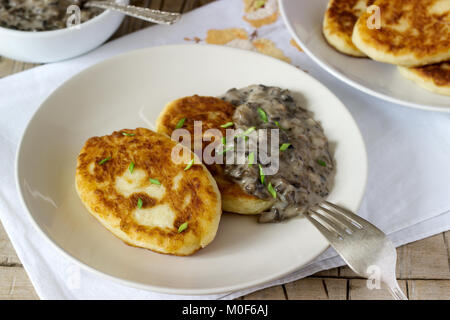 Cotolette di patate o pancake con salsa di funghi e le cipolle verdi. Stile rustico. Foto Stock