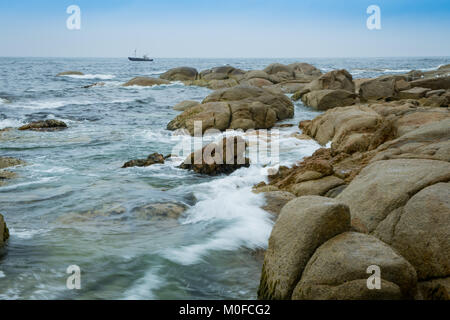 Spiaggia Binalong su Tasmania 's Bay di incendi chiamato a causa di incendi aborigene sulla costa e il luminoso lichene arancione che copre le rocce di marmo Foto Stock
