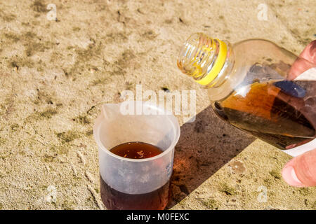 Versando il glifosato spessa soluzione in un beaker Foto Stock