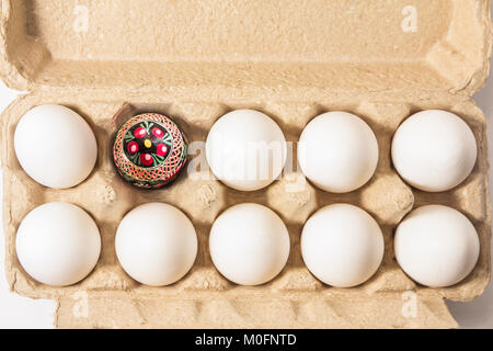 Fatte a mano la cultura folk decorato uovo di pasqua imballato in cartone riciclato box tra pianura bianco uova di pasqua presto in arrivo. Foto Stock