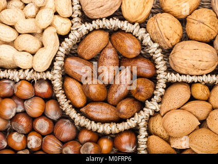 Cestello portata in vari tipi di dadi in gusci di noci pecan, mandorle, nocciole, arachidi e noci su sfondo bianco Foto Stock