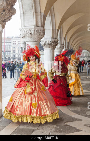 Il Carnevale di Venezia, Venezia, Italia. Tre donne in costumi classic in posa presso il Palazzo dei Dogi, San Marco, sotto gli archi Foto Stock