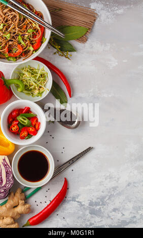 Vegano sano Tagliatelle di grano saraceno con un mix di verdure, germogli e dado-la salsa di soia. Vegetariano padthai soba noodles in bianco ciotola e ingredienti su Foto Stock