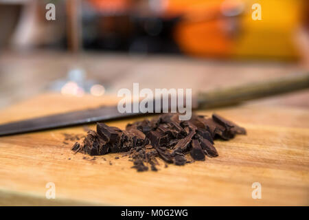 Chiudere l immagine del cioccolato sbriciolati su tavola di legno e il coltello Foto Stock