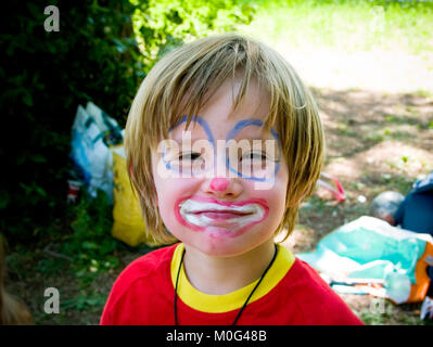 Close up ritratto di un sorridente sei anno vecchio ragazzo con il suo volto dipinto come un clown Foto Stock