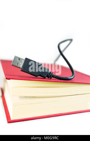 Porta USB Calbe proveniente al di fuori di un libro con i coperchi di colore rosso. Concetto di ebook, audio libro di un concetto o di tecnologia dell'informazione. Isolato su bianco. Foto Stock