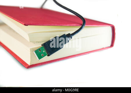 Porta USB Calbe proveniente al di fuori di un libro con i coperchi di colore rosso. Concetto di ebook, audio libro di un concetto o di tecnologia dell'informazione. Isolato su bianco. Foto Stock