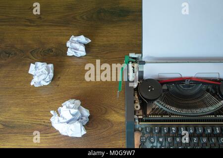 Vecchia macchina da scrivere e carta sgualcita sulla scrivania in legno. Foto Stock