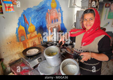 BUNDI, Rajasthan, India - 10 dicembre 2017: Ritratto di una donna nella sua cucina presentando un pasto tradizionale (thali) Foto Stock