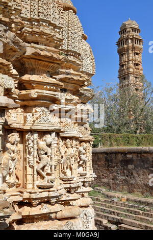 Le sculture di Samideshwar tempio indù con la torre della vittoria in background, situato all'interno della fortezza (Garh) di Chittorgarh, Rajasthan, India Foto Stock