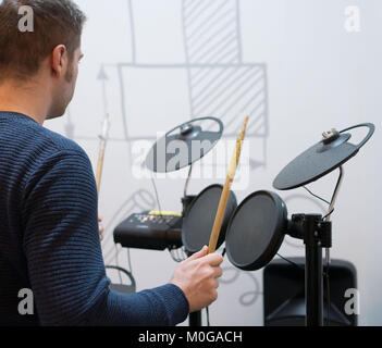 L'uomo gioca su batterie elettroniche. Vista posteriore. Foto Stock