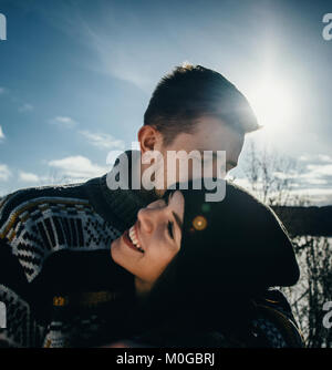 Gioiosa carino coppia abbraccia. Giovane uomo in un maglione abbraccia una ragazza e la bacia il d'inverno. Il concetto di un rapporto di successo e di momenti felici Foto Stock