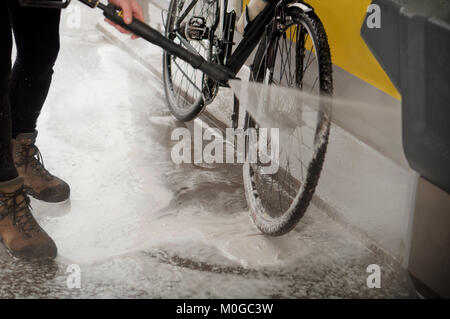 L'uomo il lavaggio della moto con un forte getto di acqua di lavaggio, la moto dopo il viaggio Foto Stock