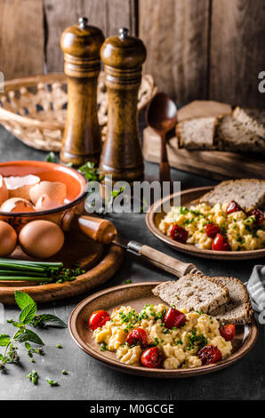 Uova strapazzate con erbe aromatiche, pomodori arrosto, erba cipollina Foto Stock