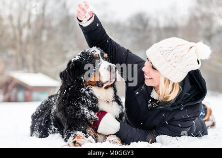 Donna che abbraccia il suo cane nella neve Foto Stock