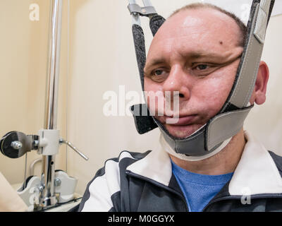 L uomo nel collo macchina di trazione per la fisioterapia Foto Stock