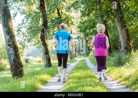 Lunghezza piena vista posteriore di una coppia senior jogging insieme outdoo Foto Stock