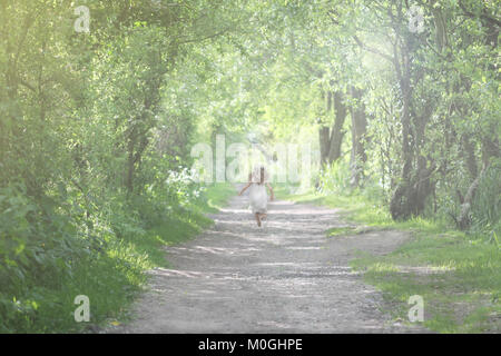 Bambina che corre attraverso i boschi Foto Stock