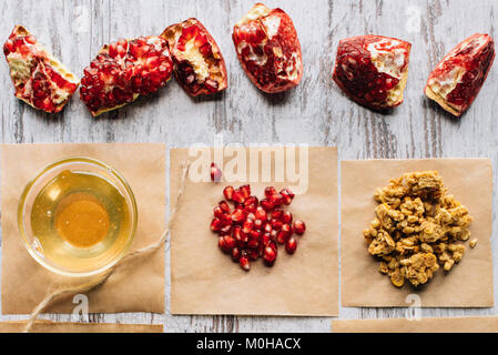 Vista dall'alto di melograni e miele per granola preparare sul tavolo Foto Stock