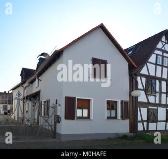 L'edificio di Hanauer Straße 38a nel quartiere Burgholzhausen di Friedrichsdorf, Germania, esemplifica l'architettura residenziale tedesca della metà del XIX secolo, caratterizzata da un tetto a falde, una facciata simmetrica e dettagli decorativi tipici dell'epoca, e contribuisce al paesaggio storico locale. Foto Stock