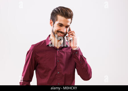 Studio shot Ritratto di giovane imprenditore che sta parlando al telefono. Foto Stock