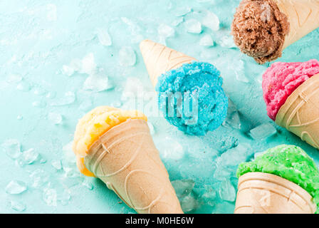 La selezione di vari luminoso multicolore di gelato in coni gelato al cioccolato - vaniglia Mirtillo Fragola pistacchio arancione, sulla luce di sole blu b Foto Stock