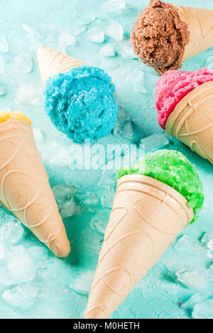 La selezione di vari luminoso multicolore di gelato in coni gelato al cioccolato - vaniglia Mirtillo Fragola pistacchio arancione, sulla luce di sole blu b Foto Stock