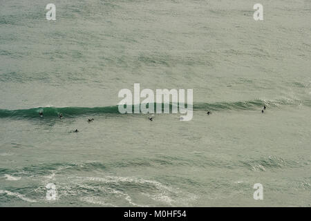 Surfers la cattura di un'onda di Piha Beach, Isola del nord, Nuova Zelanda Foto Stock