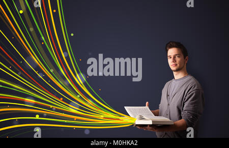 Giovane uomo a leggere un libro mentre le linee colorate sono prossimi al di fuori del libro Foto Stock