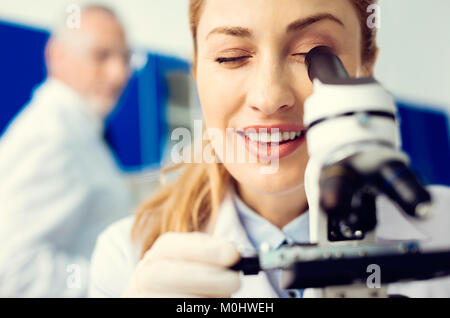Close up allegro scienziato usando microscopio in laboratorio Foto Stock