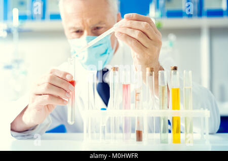 Close up uomo chimica di versamento del liquido nel tubo di prova Foto Stock