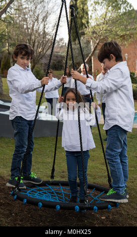 Fratelli Minori giocando nel cortile su uno swing Foto Stock