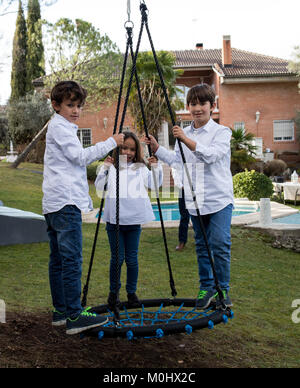 Fratelli Minori giocando nel cortile su uno swing Foto Stock