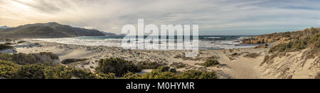 Vista panoramica di lavaggio onde su una deserta spiaggia di Ostriconi nella regione della Balagne in Corsica con Ile Rousse a distanza Foto Stock