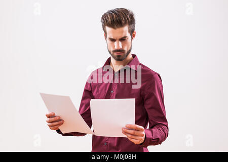 Ritratto di giovane imprenditore che sta esaminando i documenti. Foto Stock
