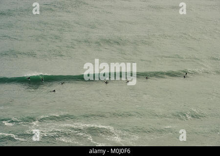 Surfers la cattura di un'onda di Piha Beach, Isola del nord, Nuova Zelanda Foto Stock