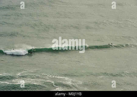 Surfers la cattura di un'onda di Piha Beach, Isola del nord, Nuova Zelanda Foto Stock